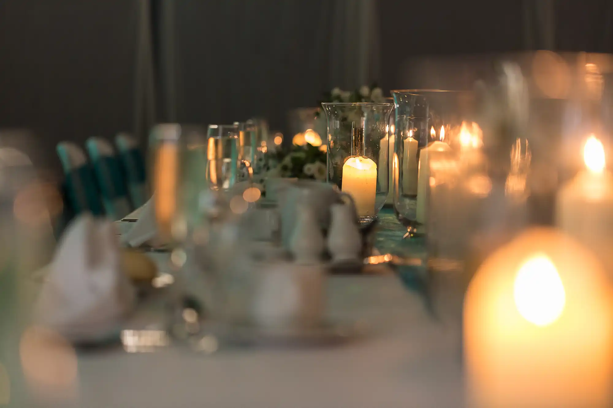Elegant dinner table setting featuring lit candles, floral centerpieces, and soft lighting, creating an intimate ambiance.