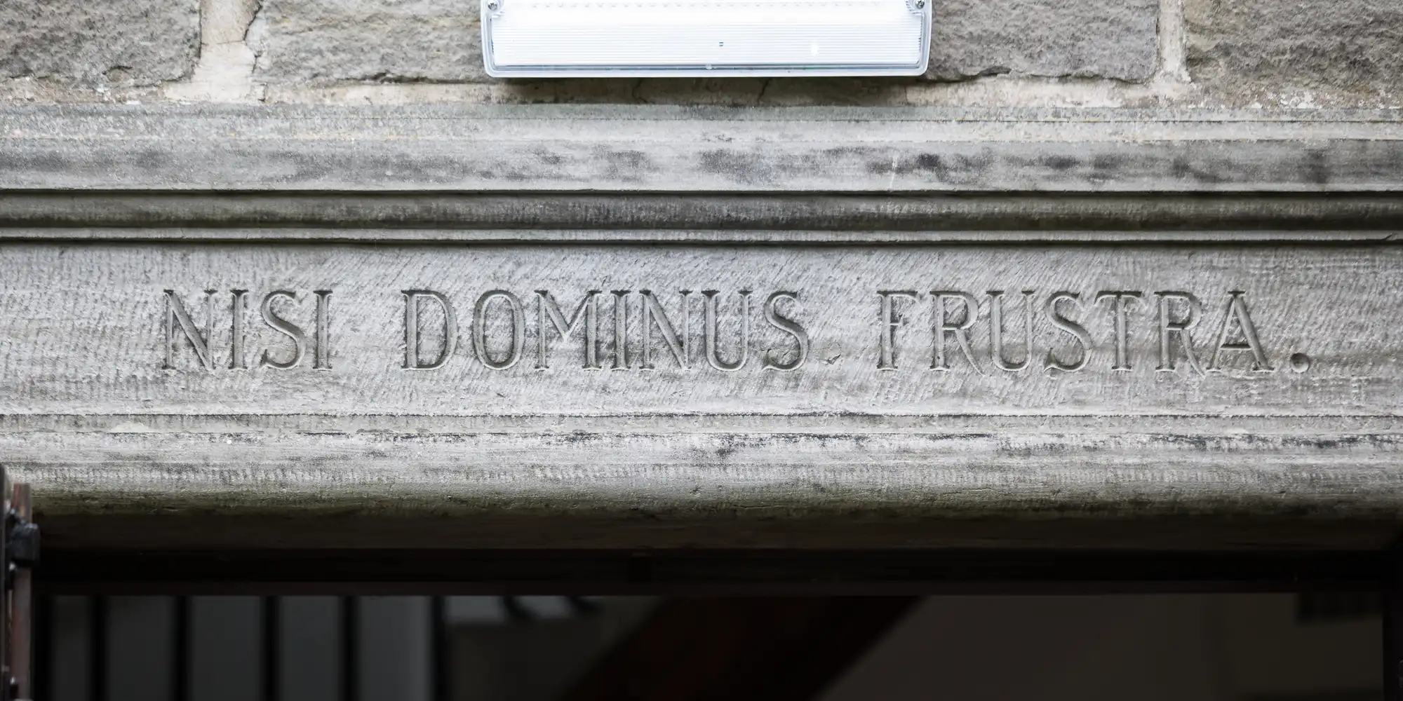 A stone lintel with the Latin phrase "NISI DOMINUS FRUSTRA" engraved on it.