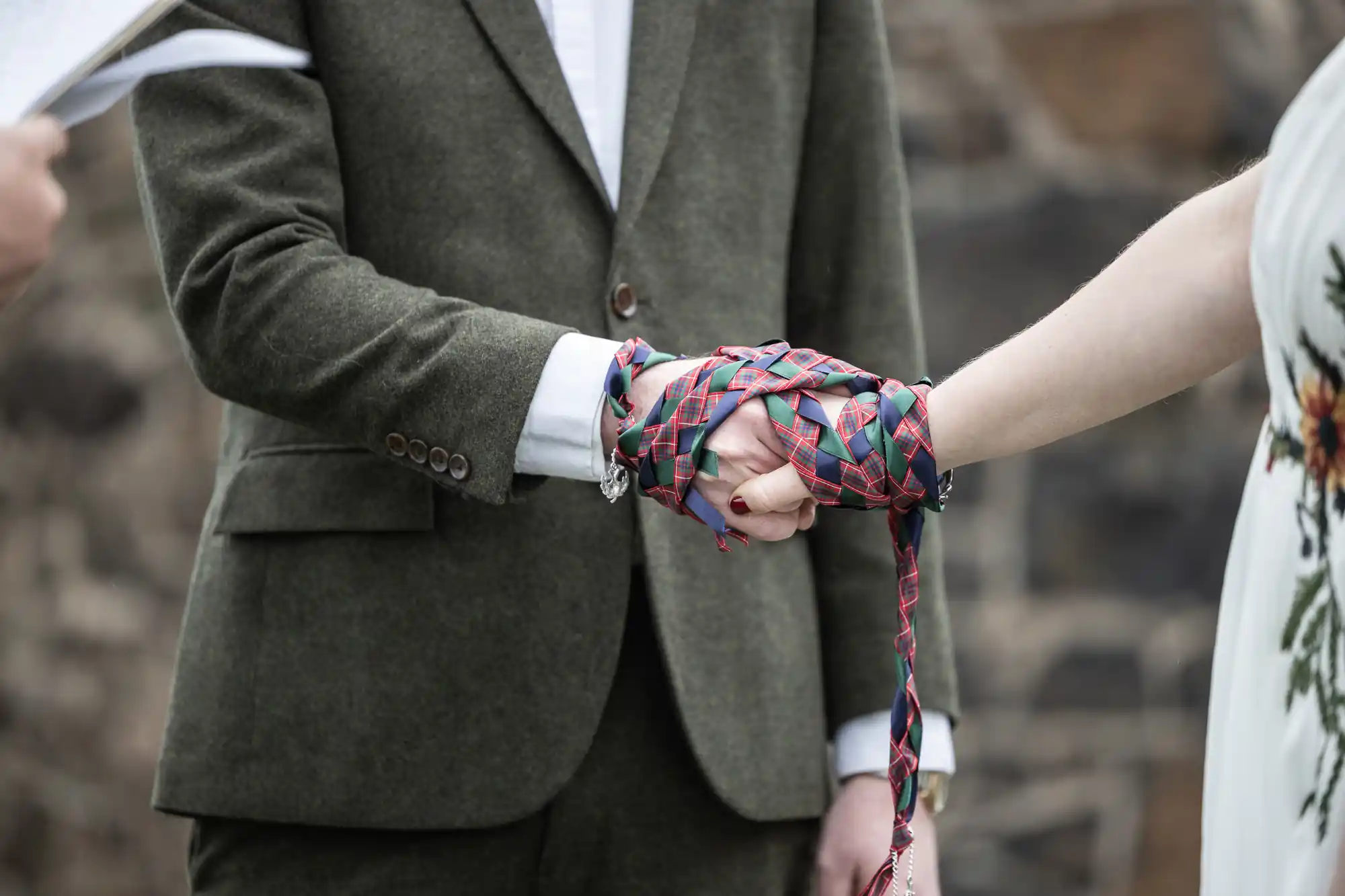 close up of hands tied with knot during marriage ceremony