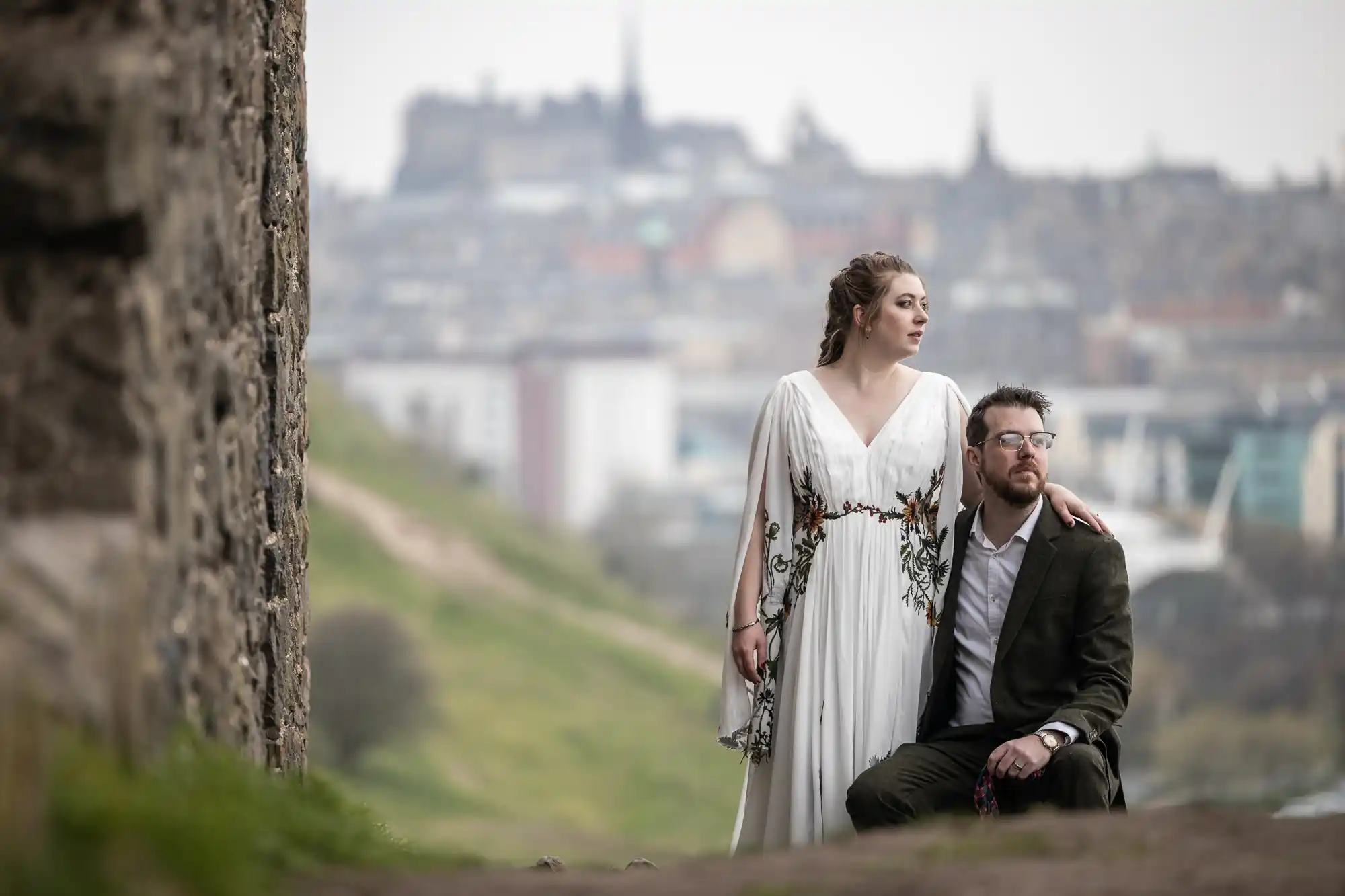 newlyweds beside ruin chapel with city backdrop