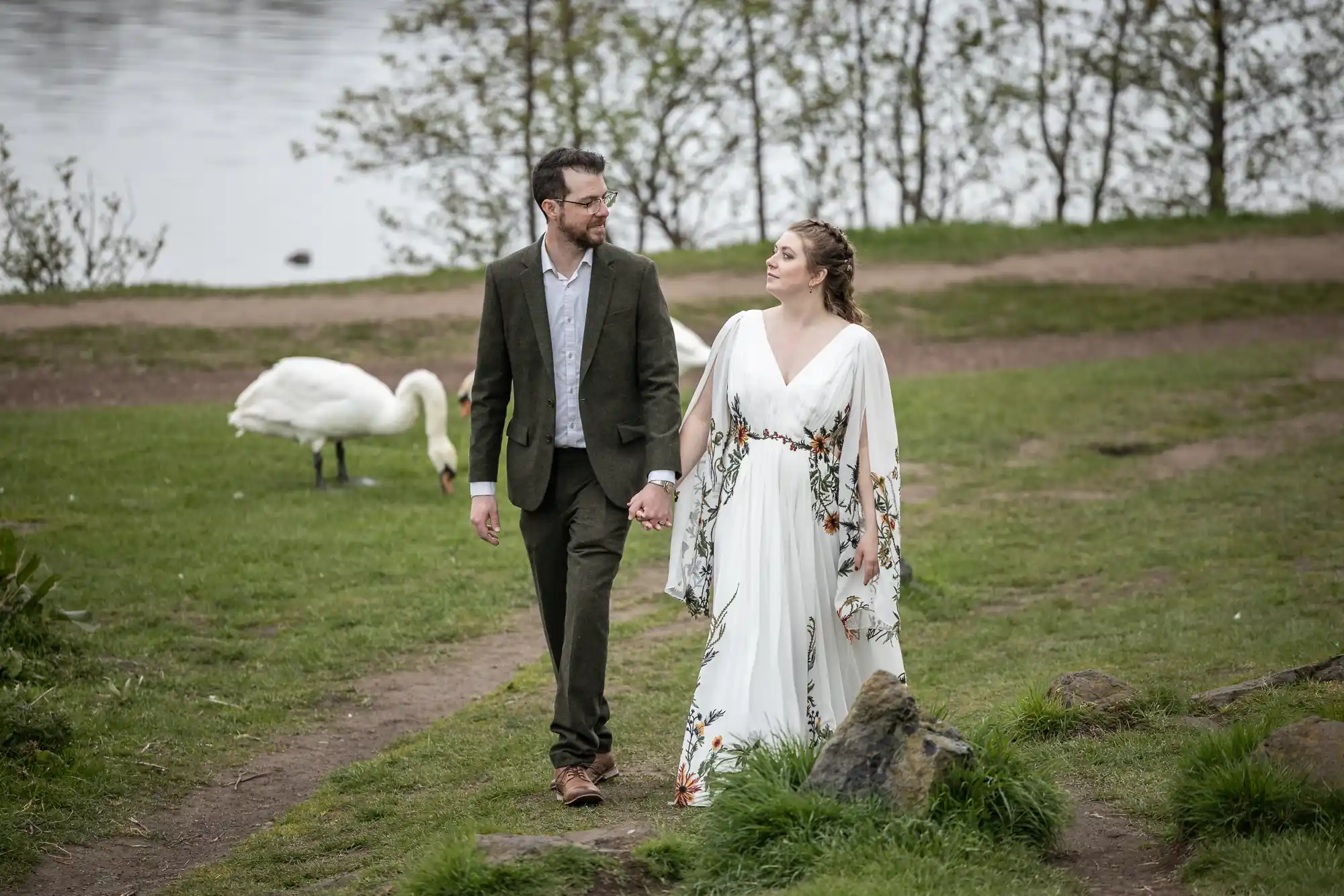 bride and groom walking next to swans