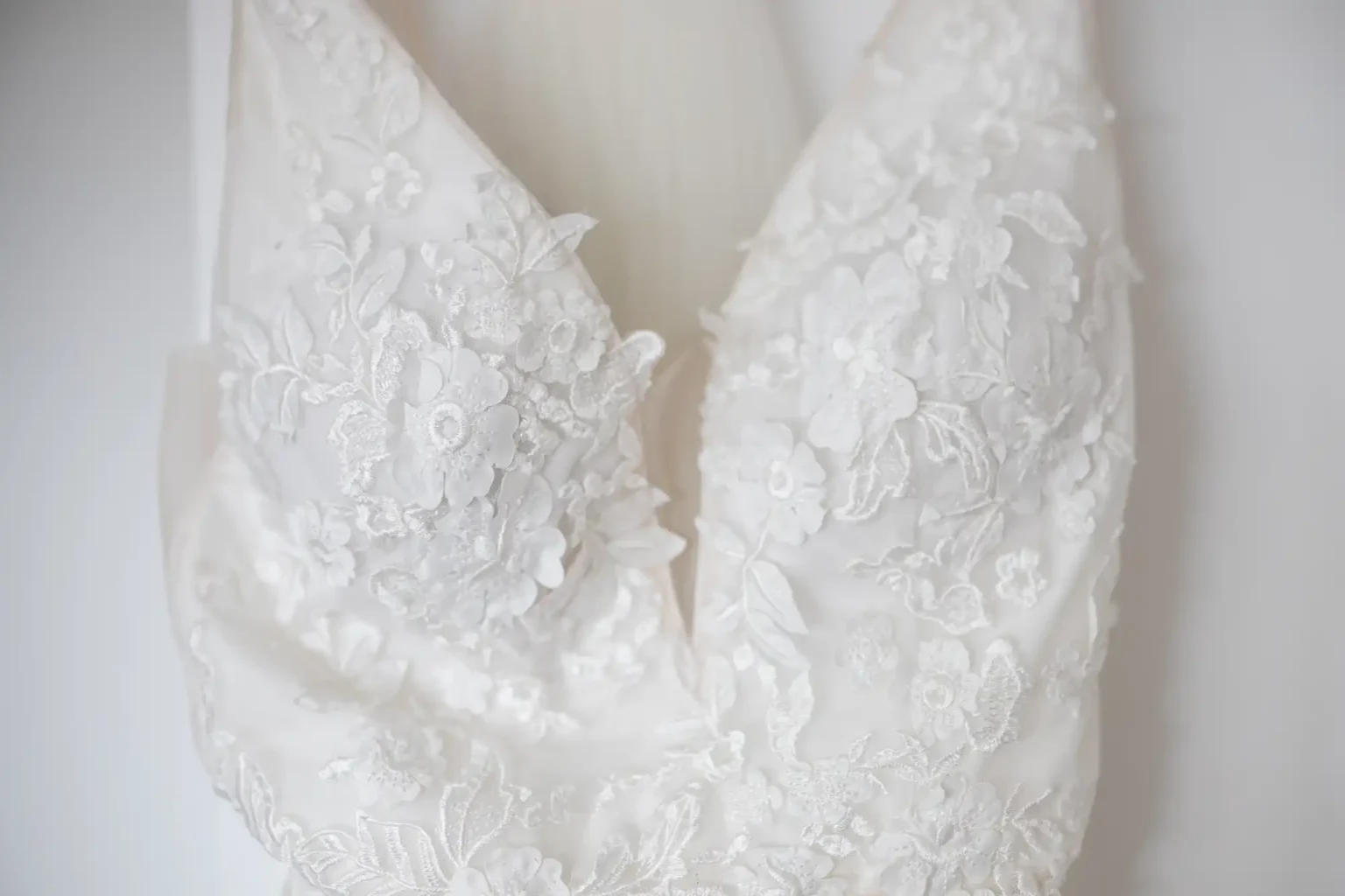 Close-up of a white lace wedding dress bodice with floral embroidery.