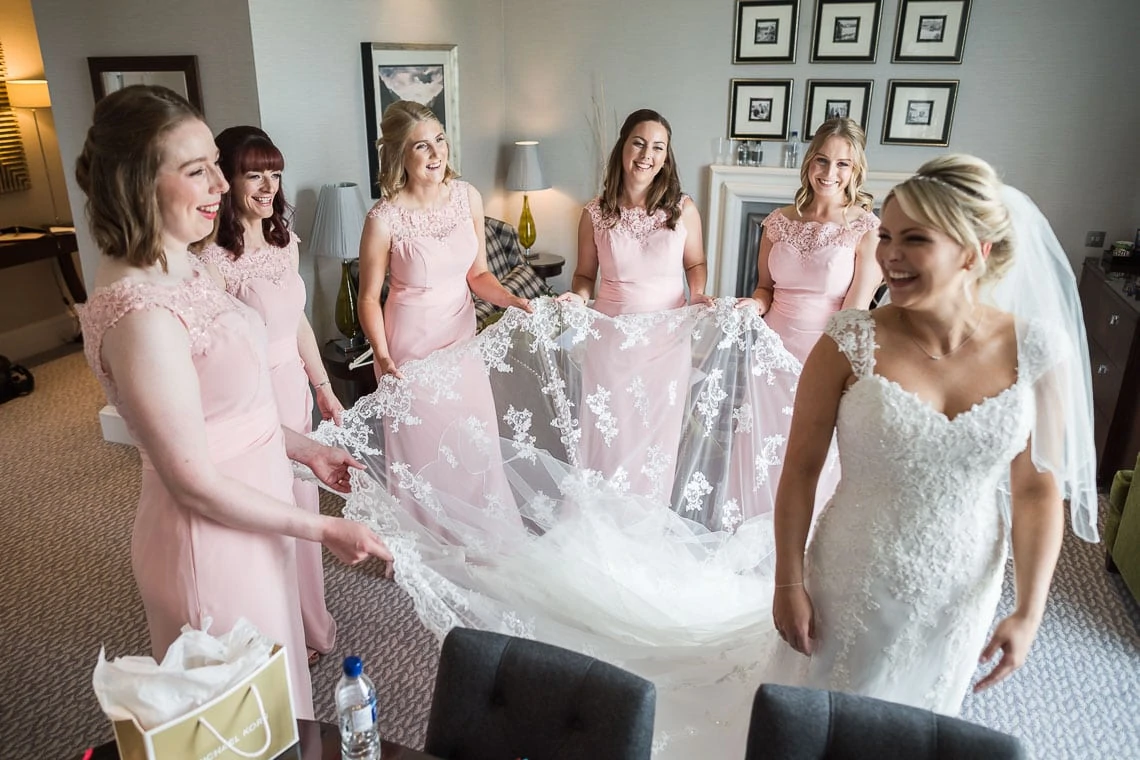 bridesmaids holding bride's veil and dress