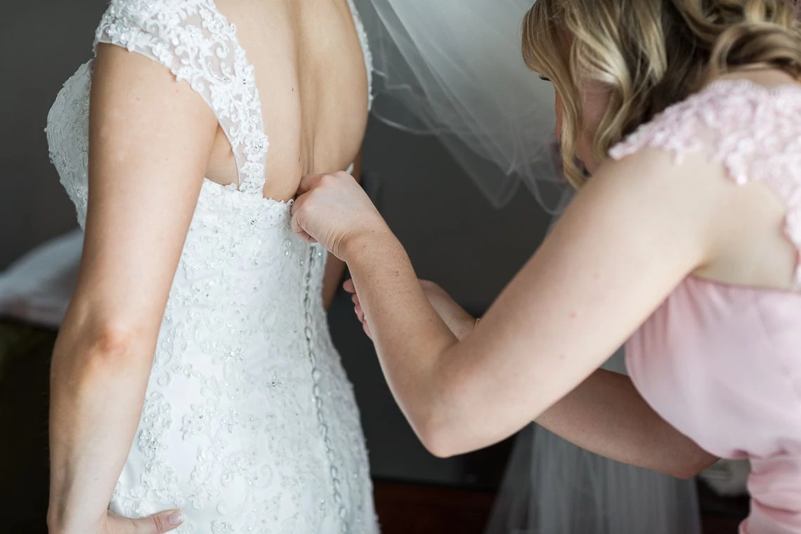 bridesmaid helps fit bridal dress