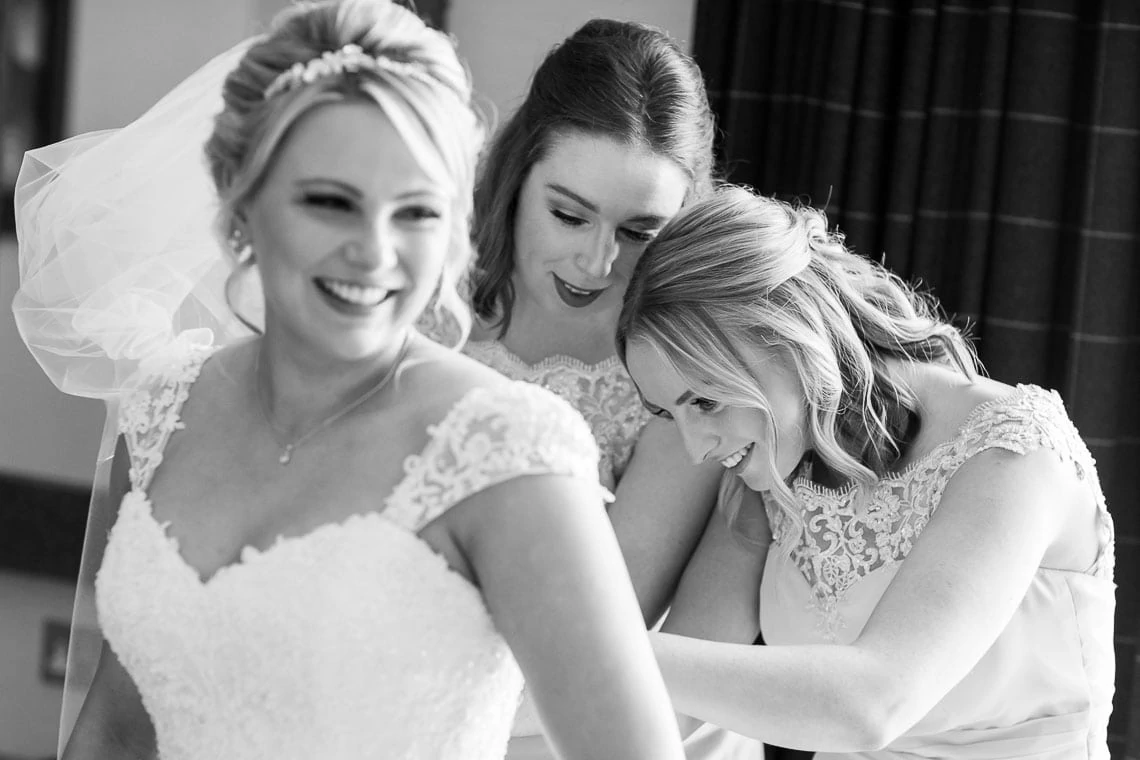 bridesmaids helps fit bridal dress