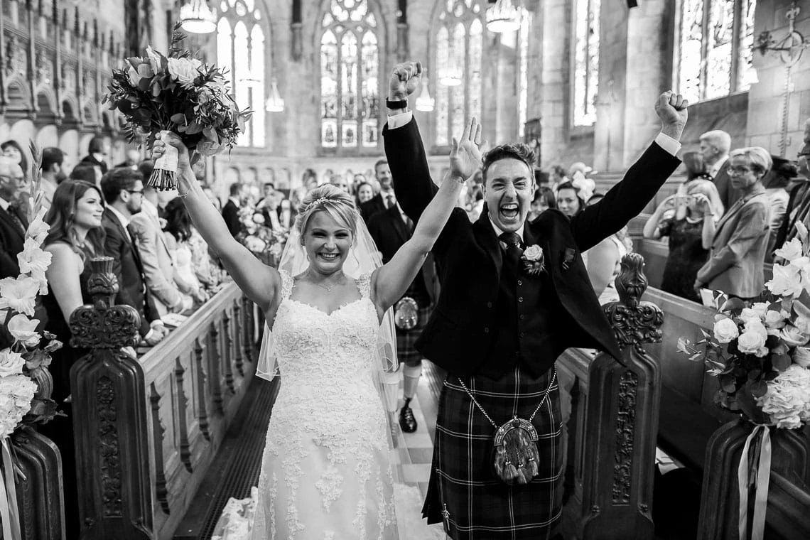 wedding recessional newlyweds walking up the aisle punching the air at St Salvator's Chapel