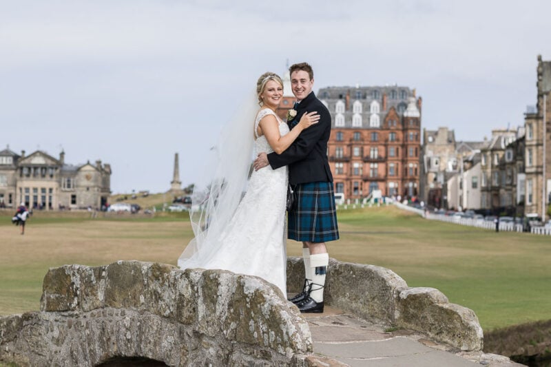 newlyweds embrace on Swilken Bridge for St Andrews wedding photographer