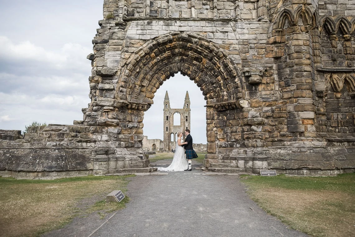 newlyweds embrace under the arch at St Andrew's Cathedral