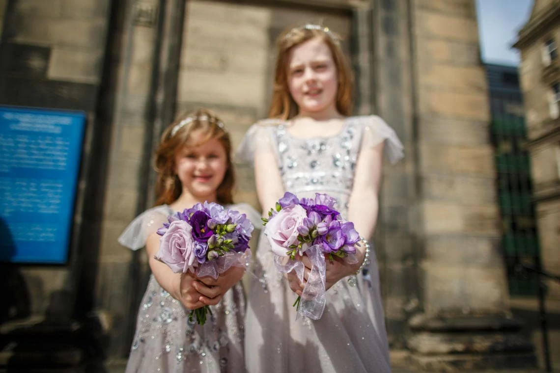 flower girls holding their bouquet of flowers outside the church