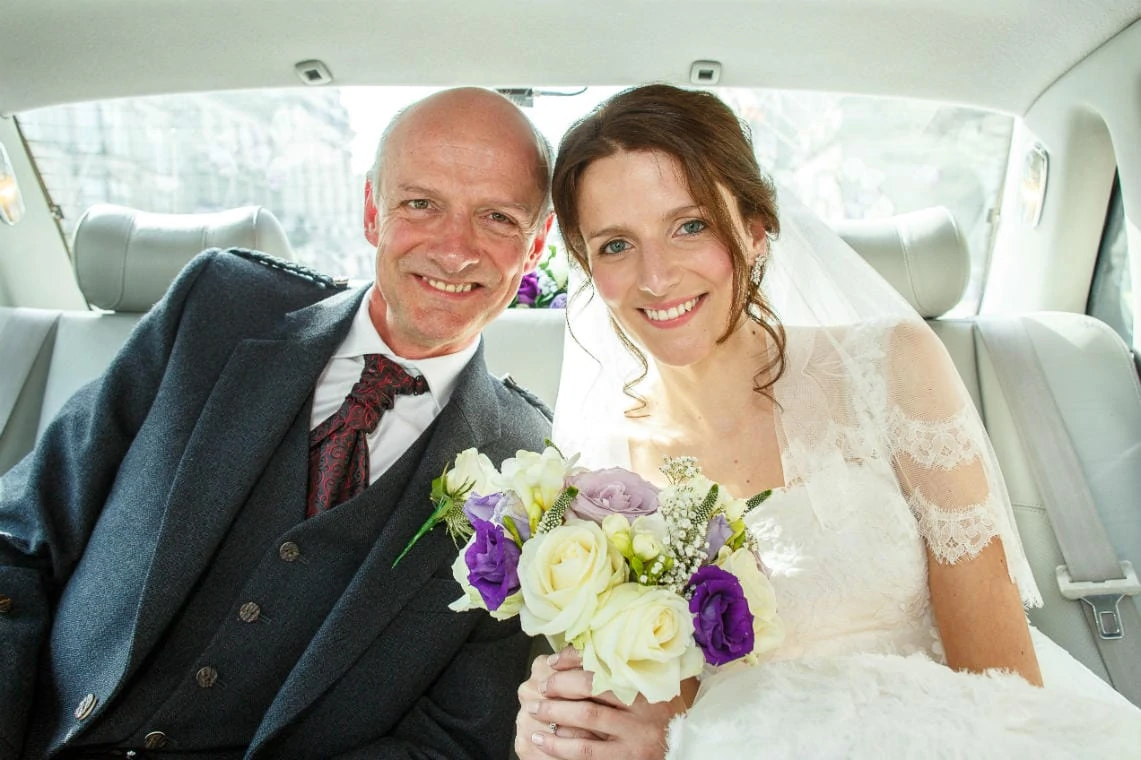 bride and her father sitting in the back of a Jaguar