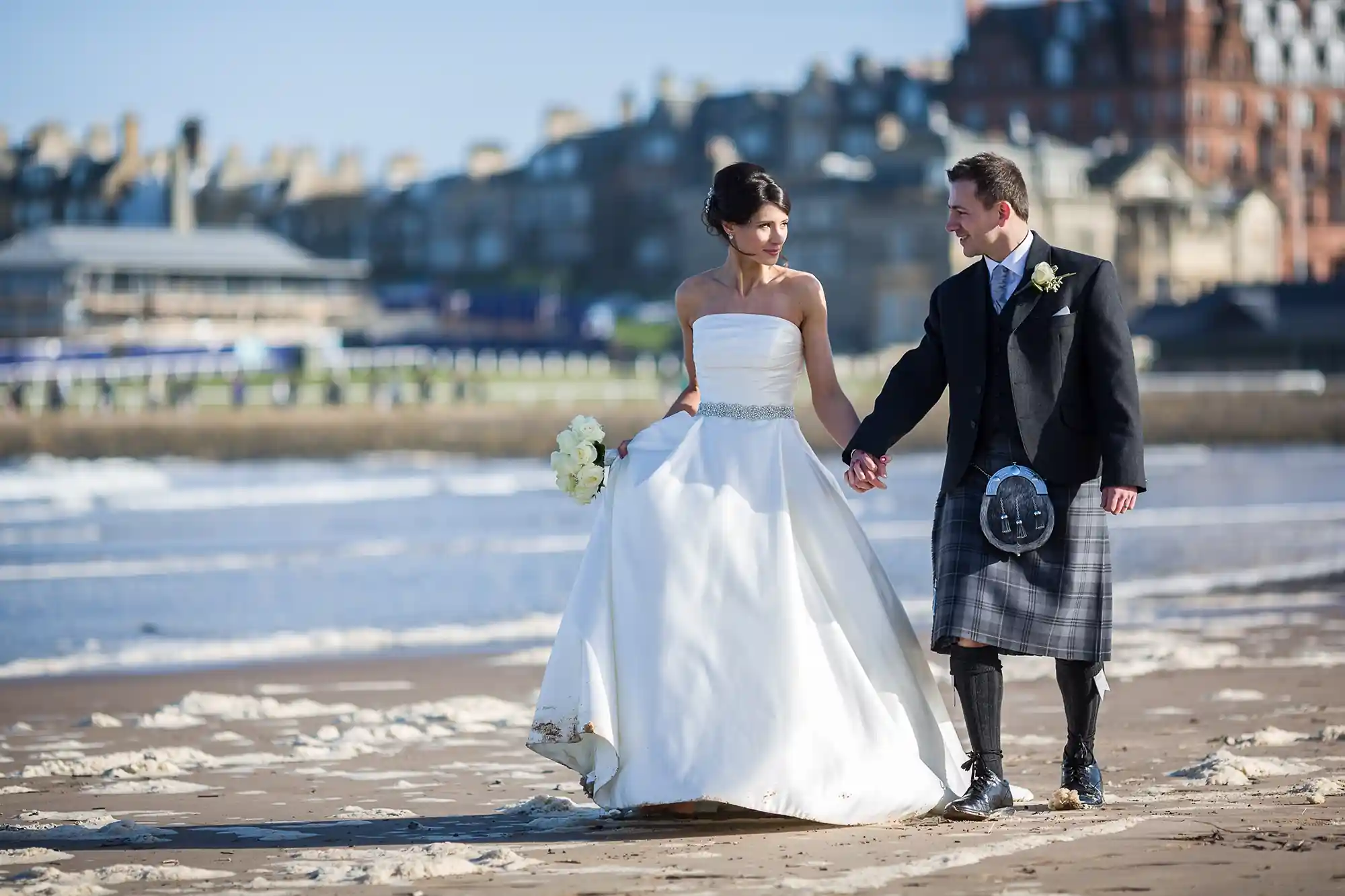Wedding photographer Fife - St Andrews beach newlyweds walking hand-in-hand
