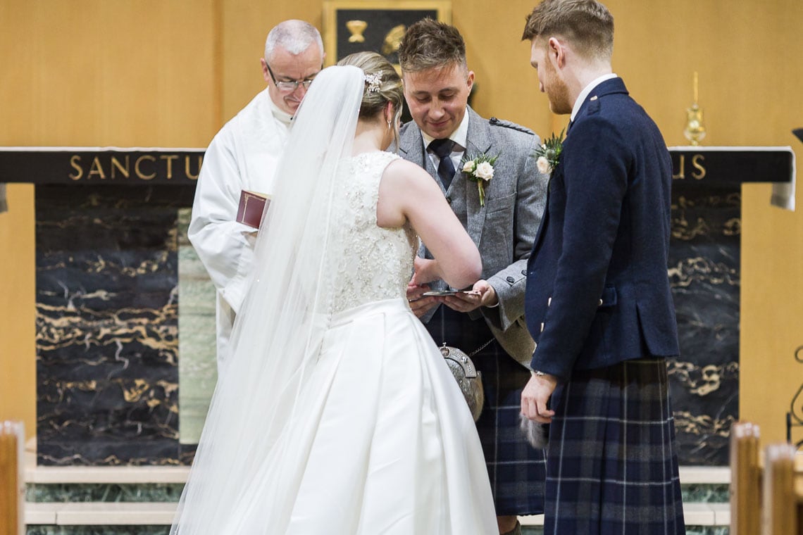 best man gives groom's ring to the bride