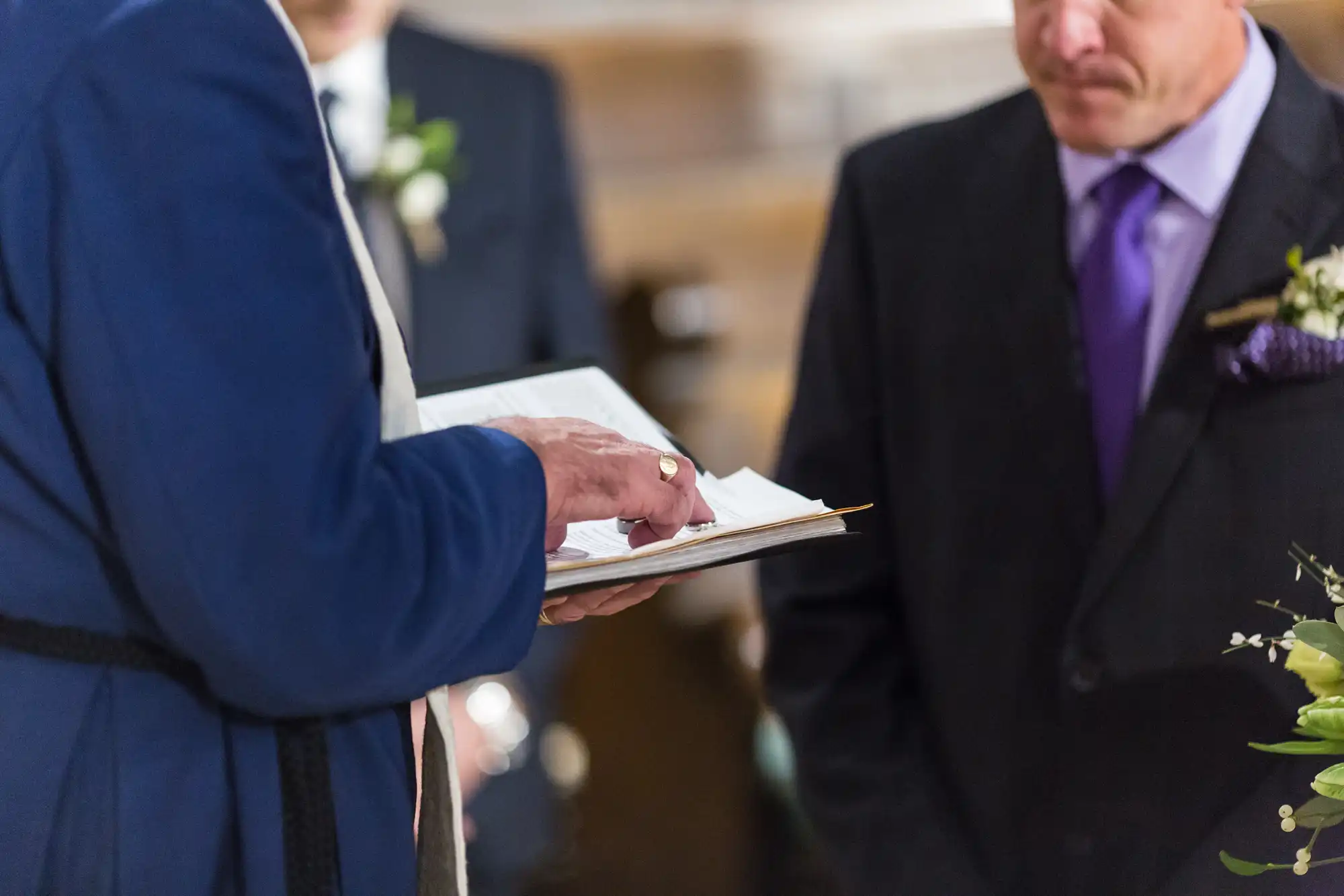 A bride and groom signing their marriage certificate, viewed close-up, with a focus on their hands and the pen.