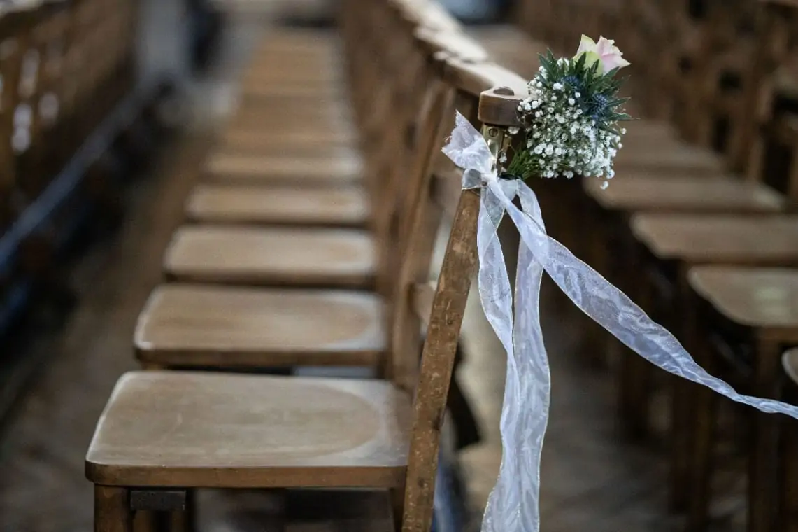 flowers tied with white ribbon on side of wooden chair