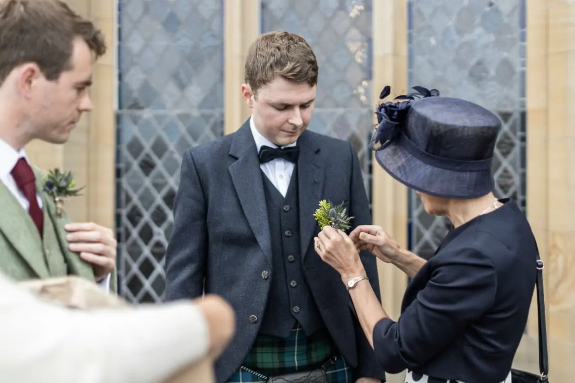 Groom getting help putting on buttonhole