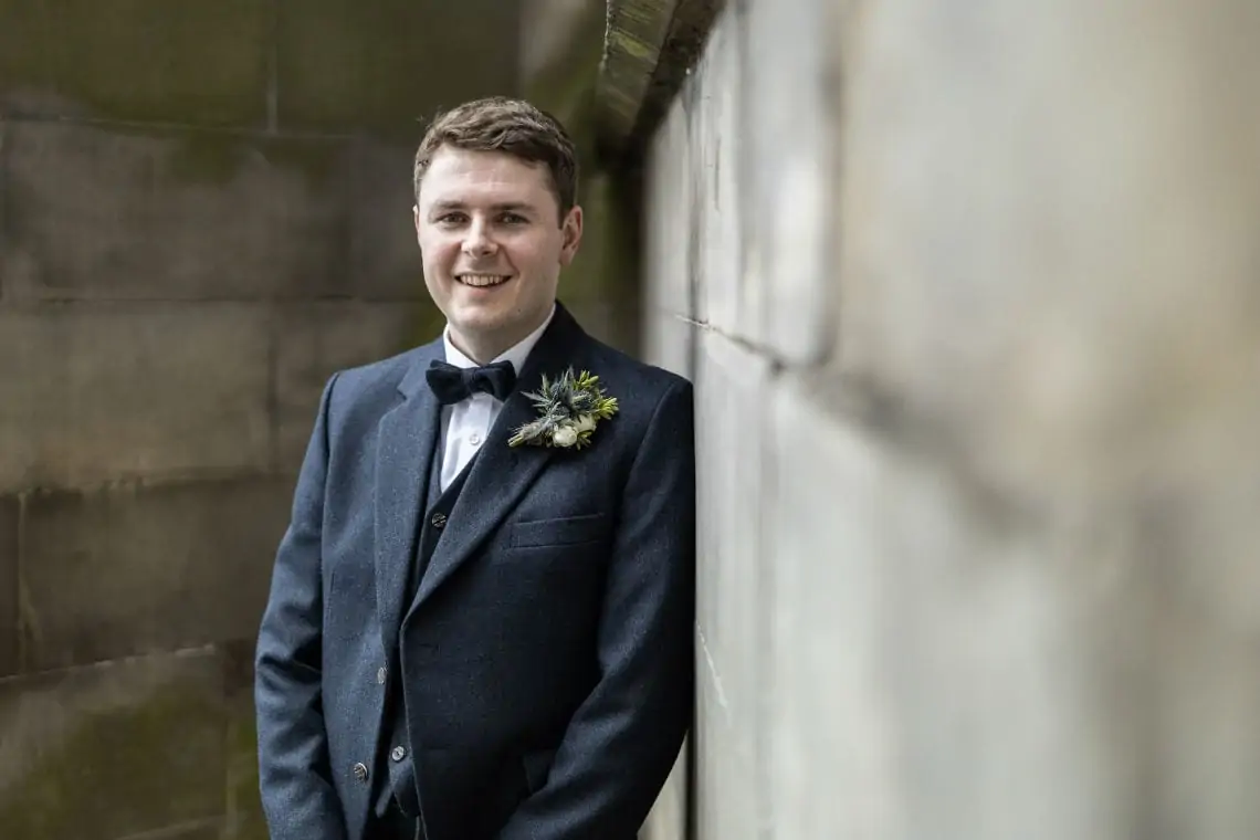 Portrait photo of groom against stone wall
