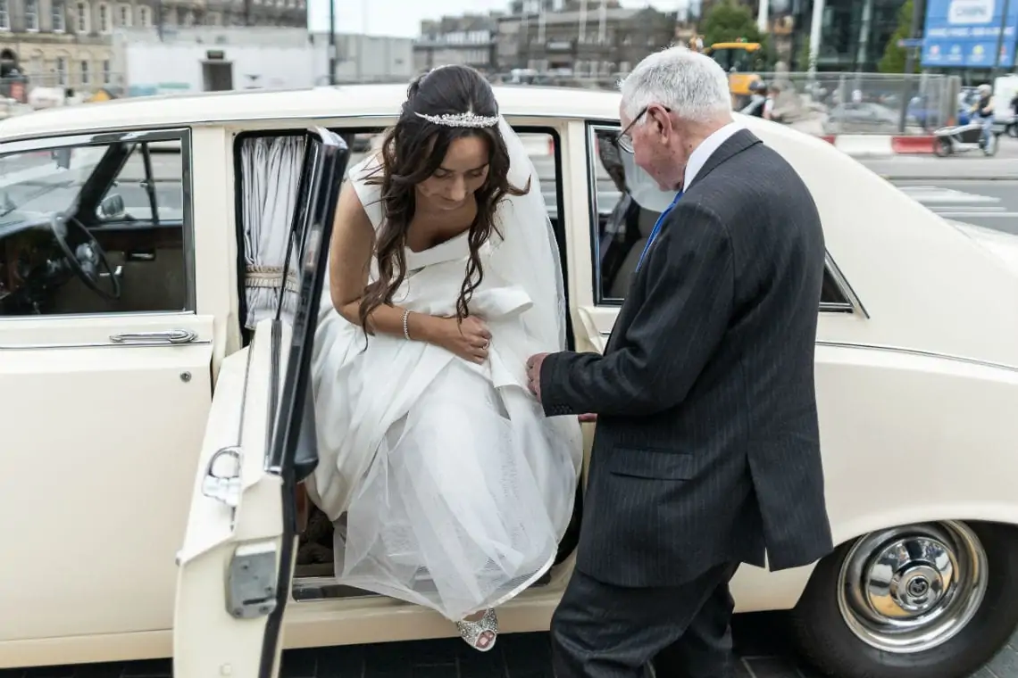 Bride getting out of car at cathedral