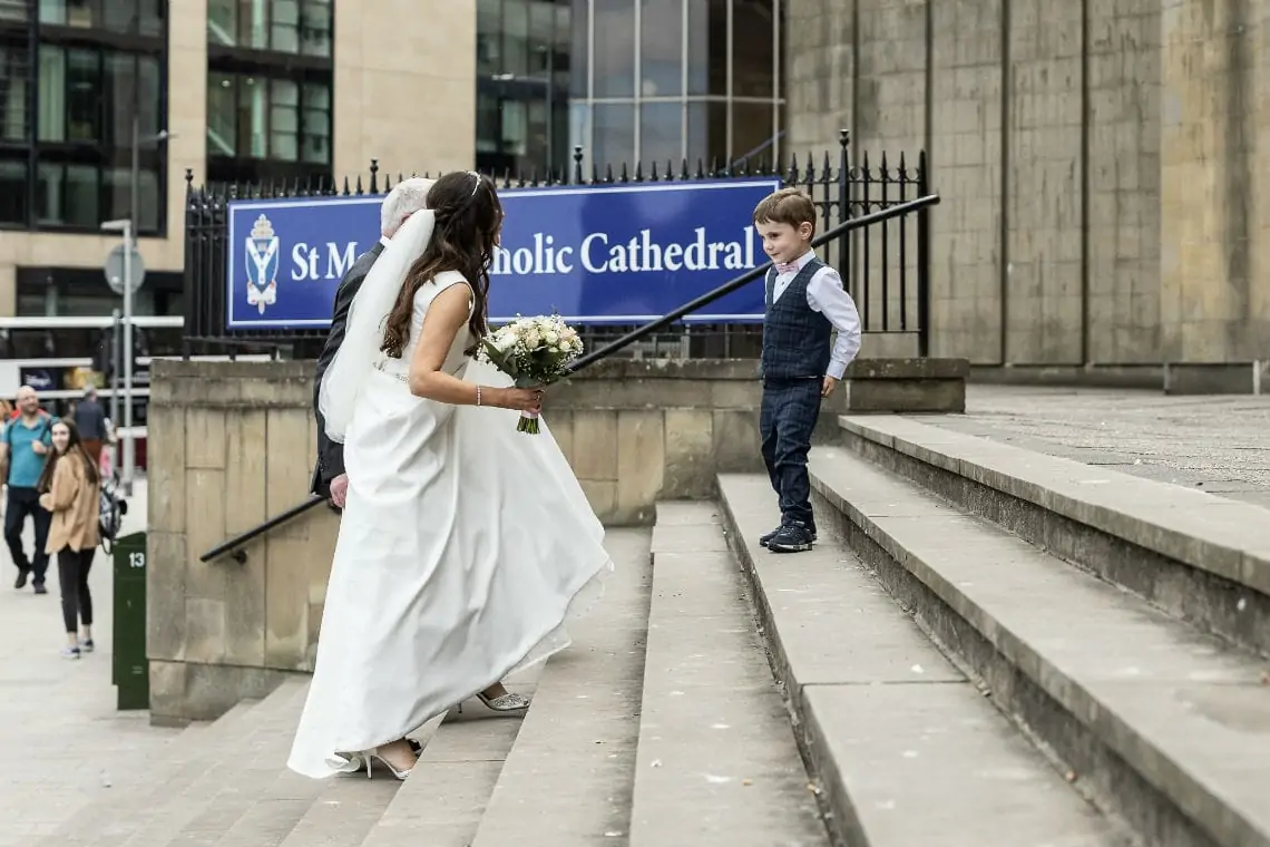 Bride being met by little boy on the steps outside the church