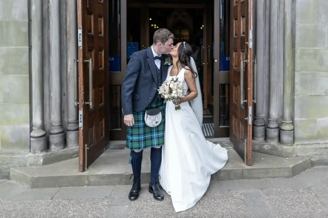 Newlyweds kissing at church doors