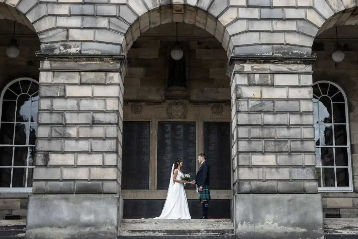 Newlyweds in the archway of the college