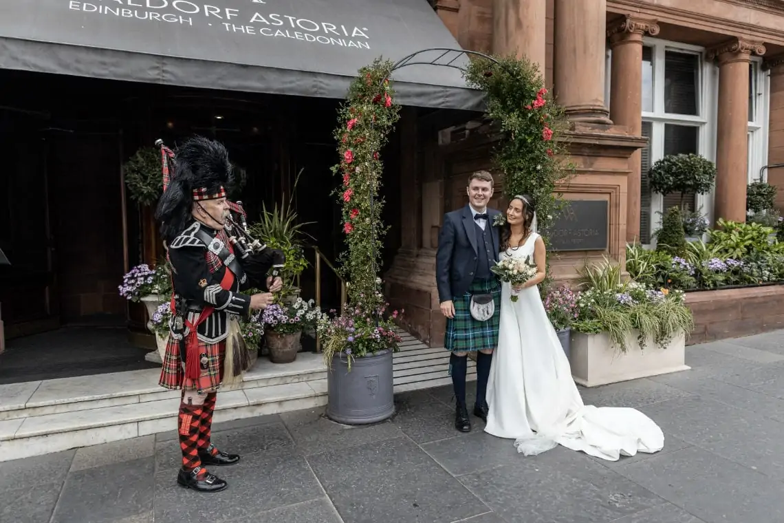 Bride and Groom pictured in front of the Waldorf Astoria with the piper