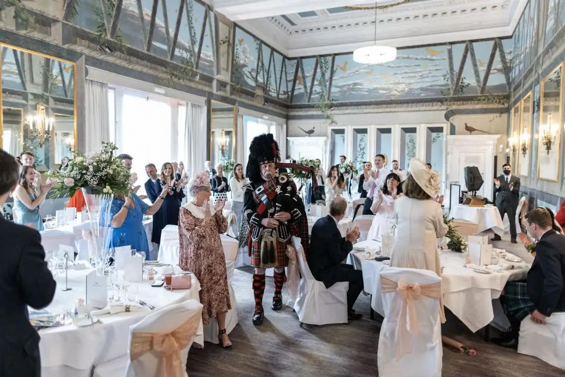 Full view of the Castle Suite with guests standing applauding the piper