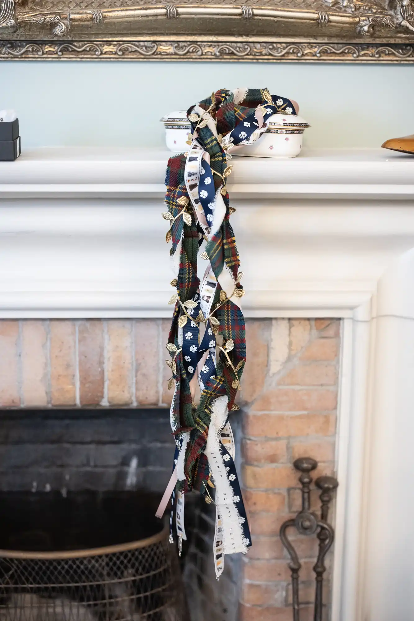 A bundle of assorted colored and patterned fabric ribbons draped over a white fireplace mantel, hanging down towards the fireplace.