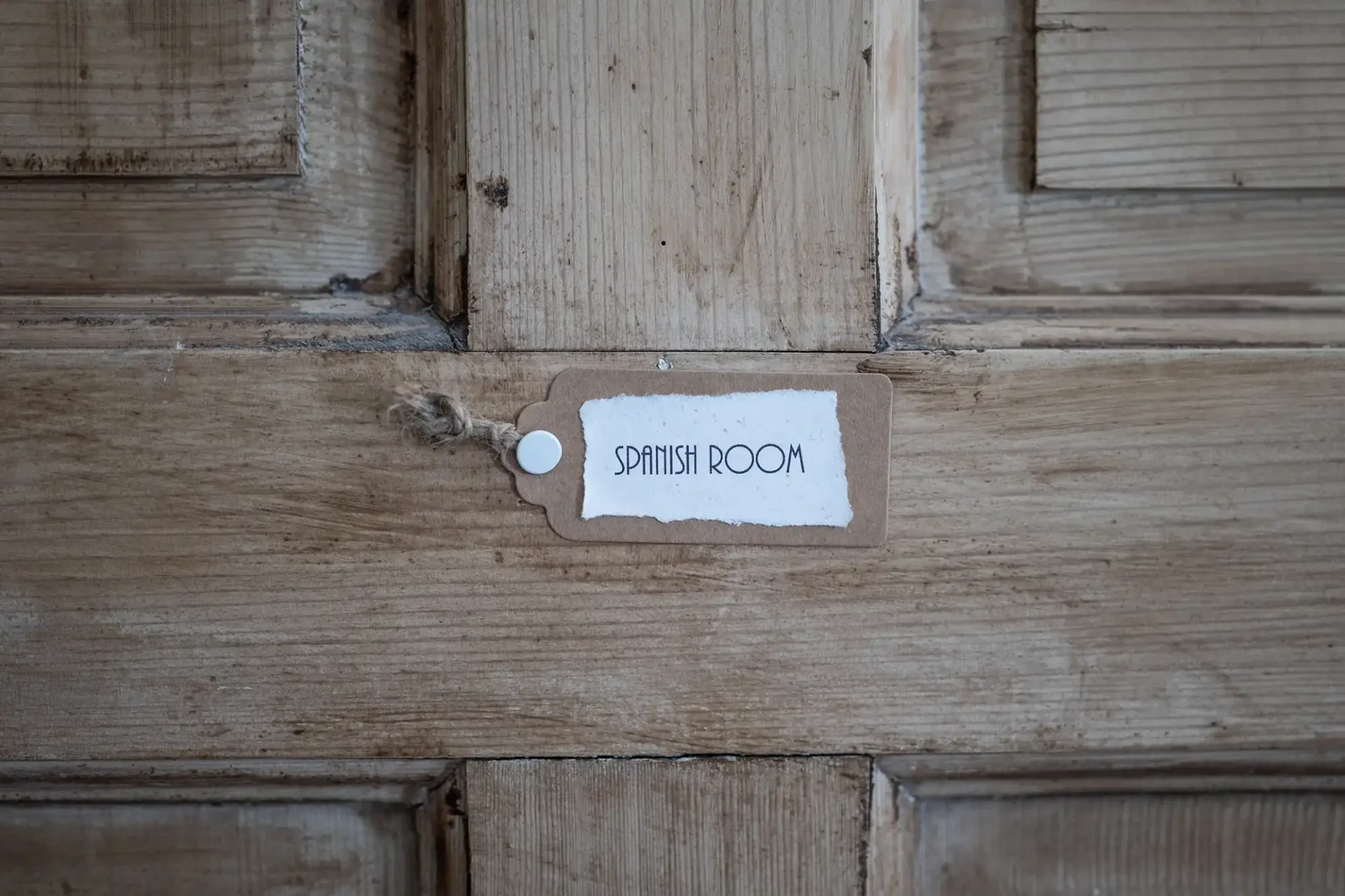 Wooden door with a small tag labeled "Spanish Room" attached to it.