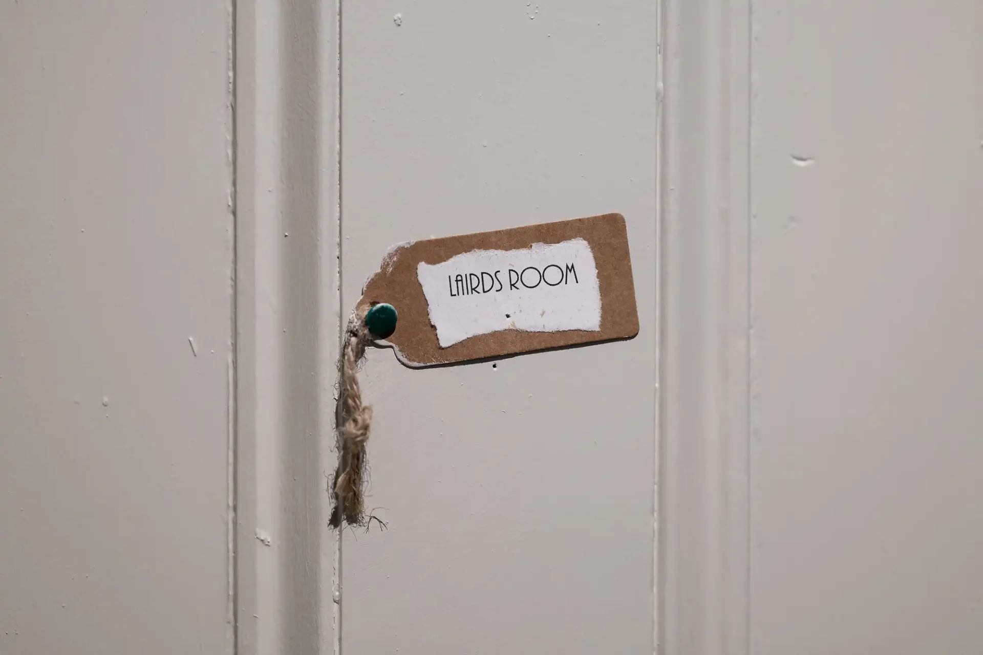 A label with "LIARS ROOM" in black text is attached to a cream-colored door with a small pin.