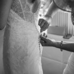 bridesmaid helping button up the bride's dress in the Forthview Suite