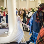 bride and groom are escorted by the piper to the top table