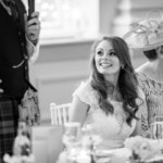 bride smiles during the groom's speech in the King's Hall