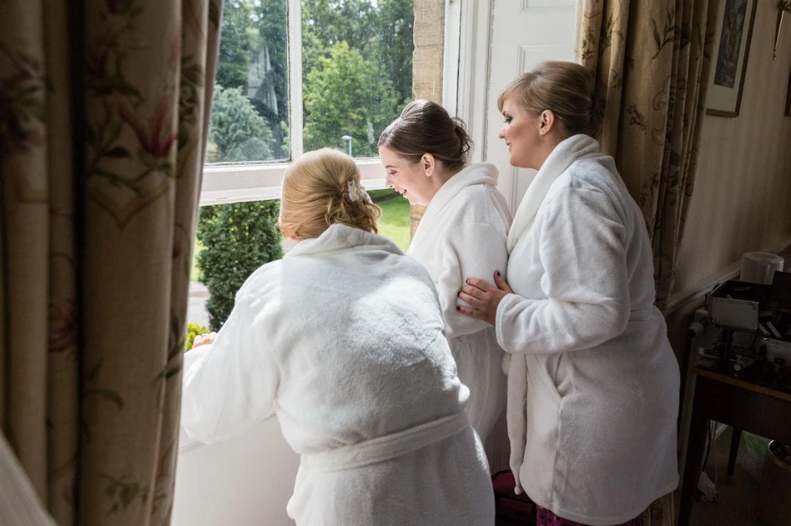 bridesmaids watching from window of room 203 as guests arriving