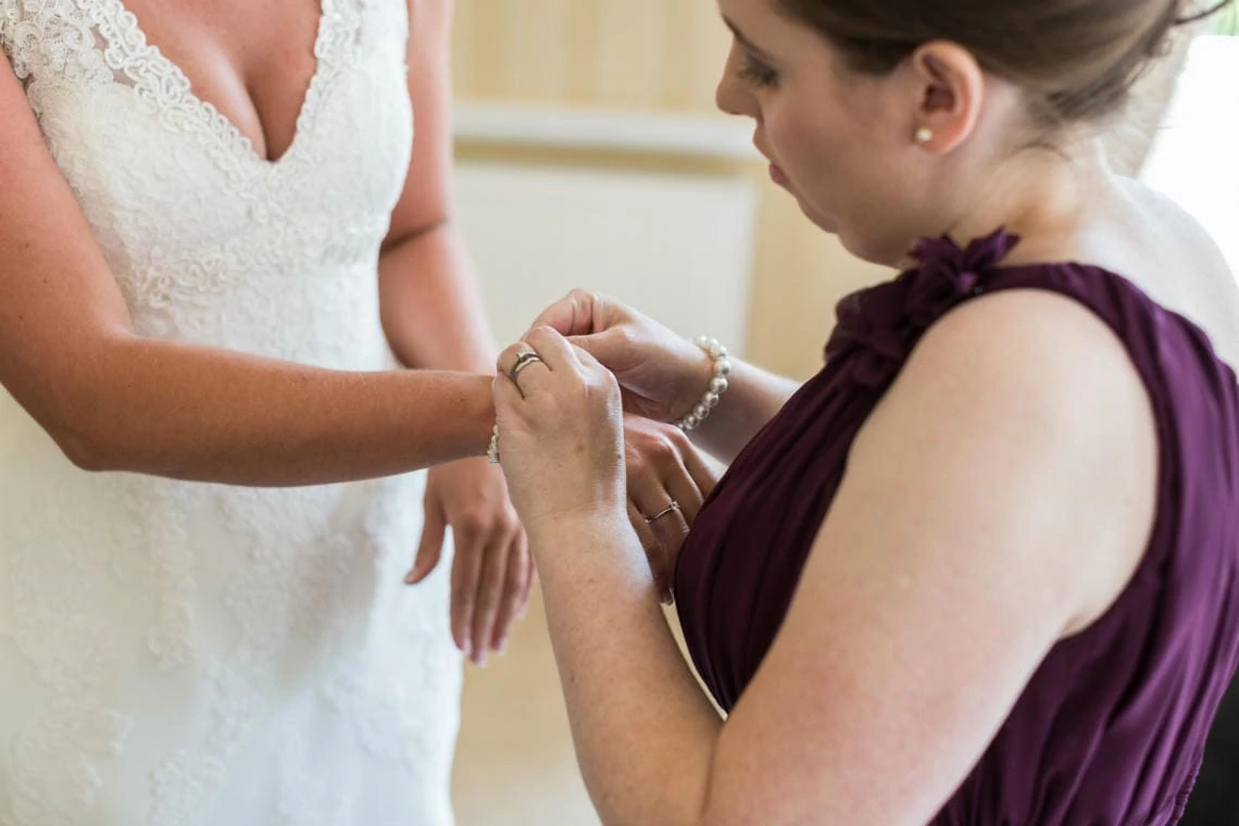 brdiesmaid helps bride put on a bracelet