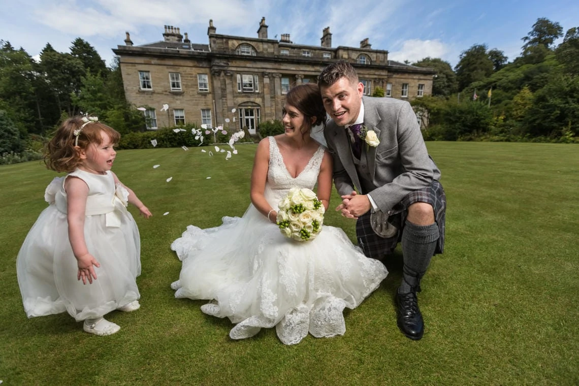 flower girl throws confetti over the newlyweds on the lawn