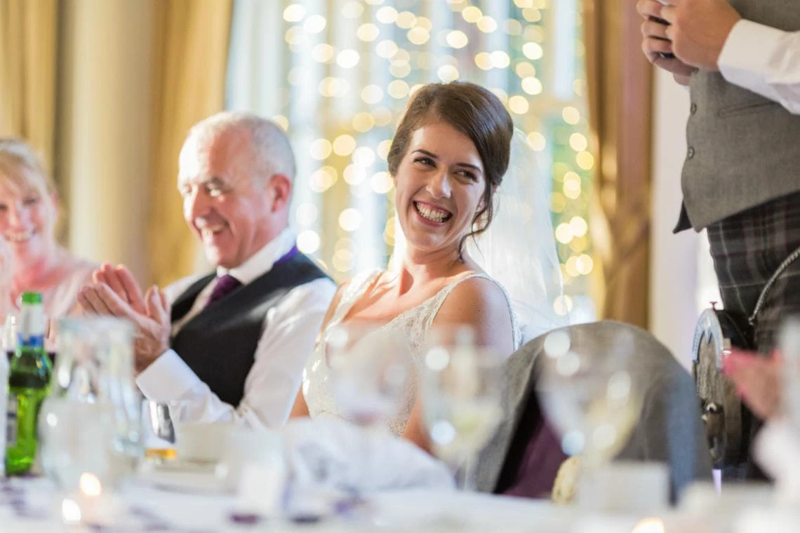 bride smiling during groom's speech