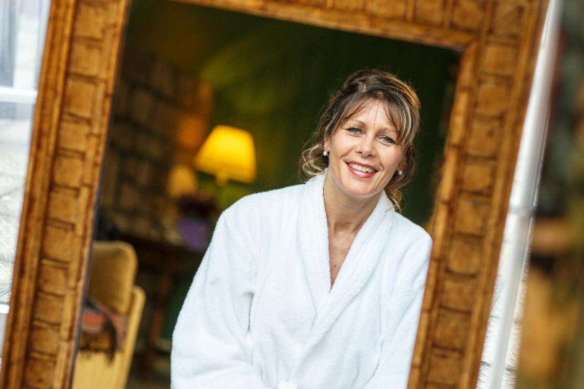 bridal preparations wearing a white robe in front of a mirror in a bedroom