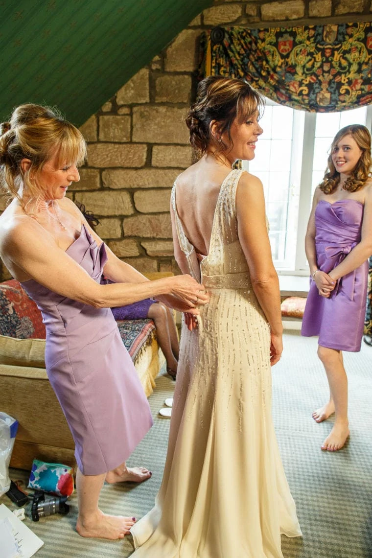 maid of honour helps bride with her dress