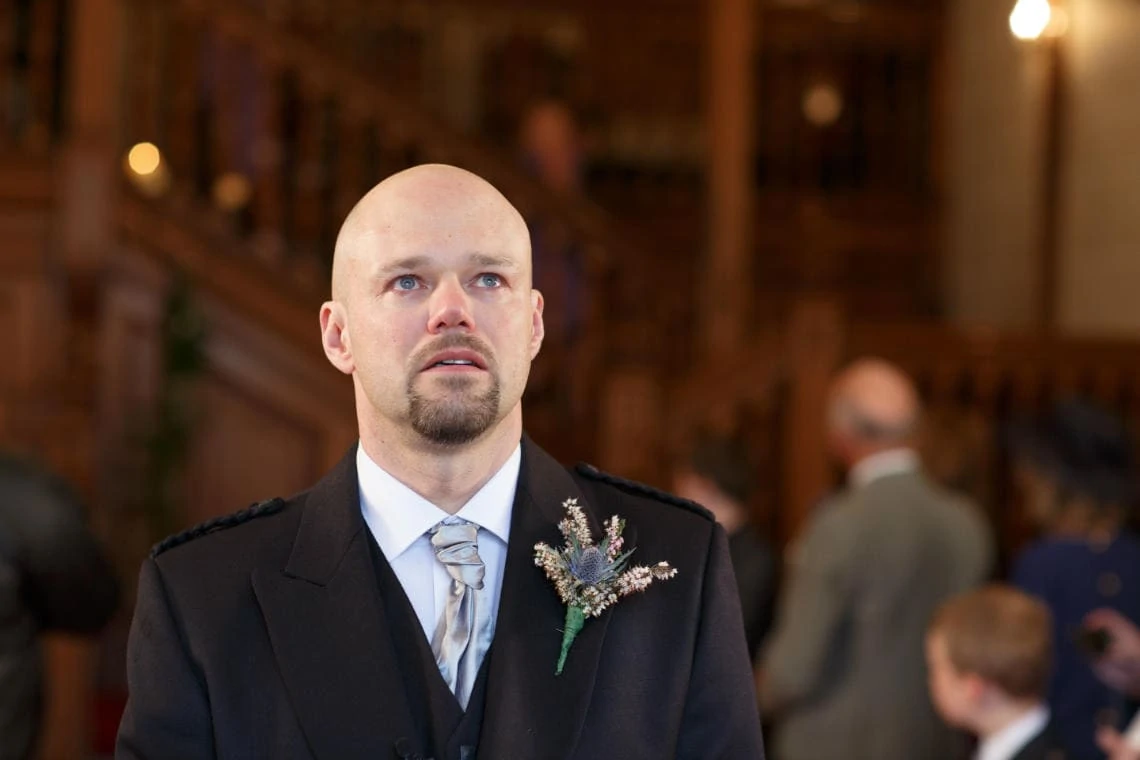 teary-eyed groom waits for the bride in the chapel