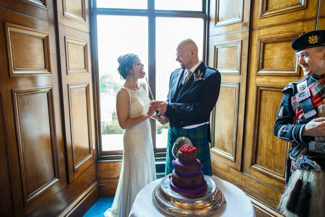 bride licks the knife after cutting the cake in the Ramsay Suite