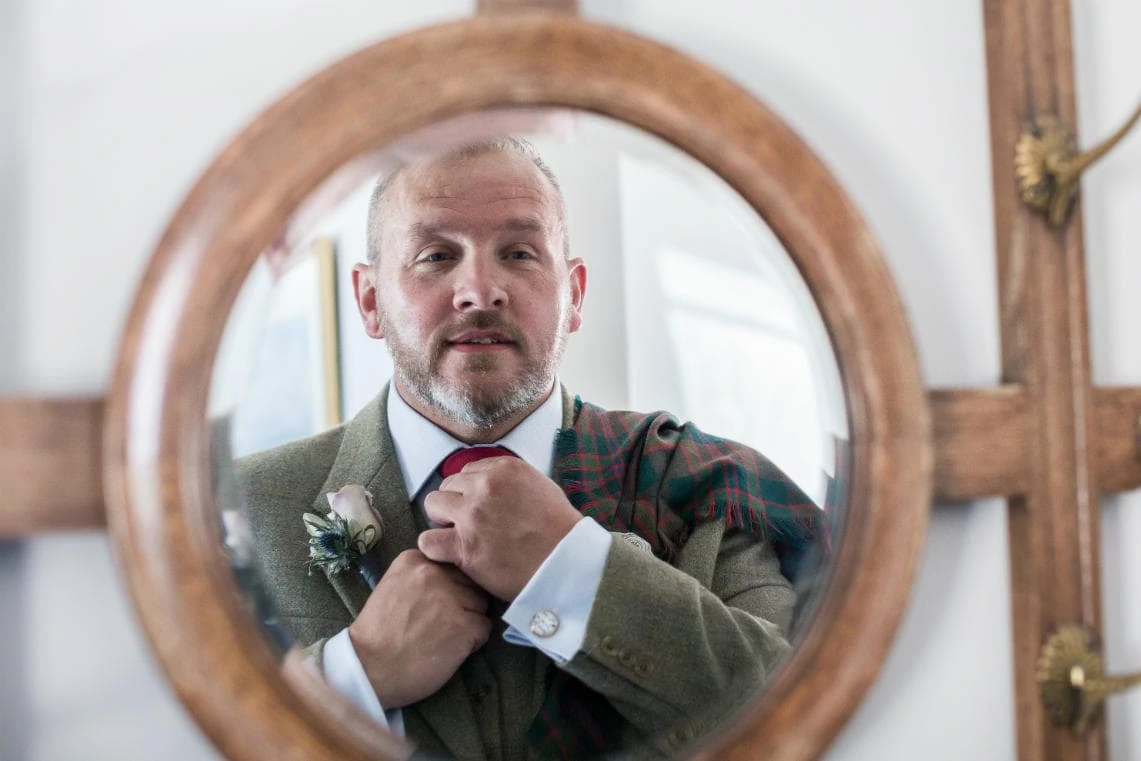 groom fixing tie in front of mirror