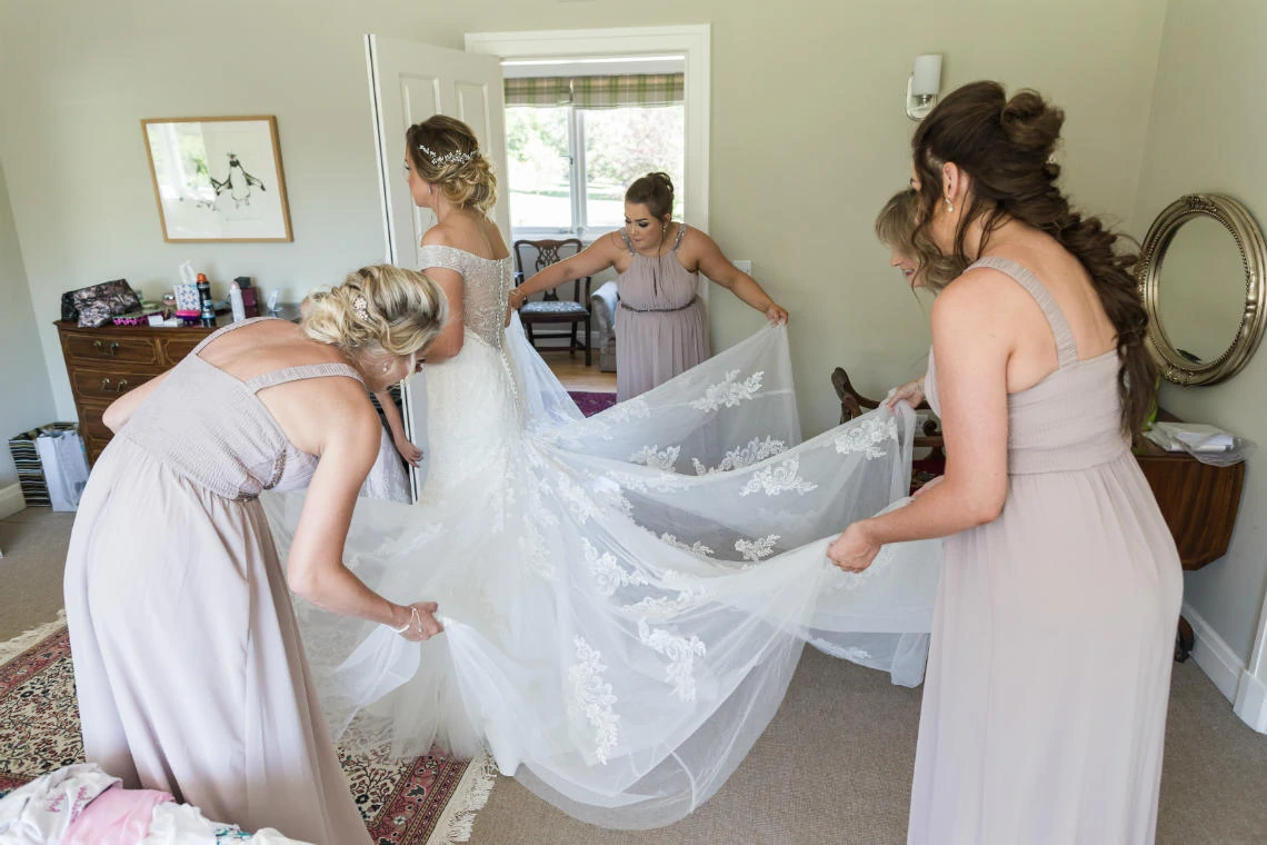 bridesmaids sorting the back of the wedding dress making sure it was lying straight