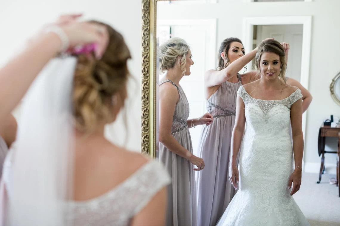 bridesmaids putting wedding veil on bride