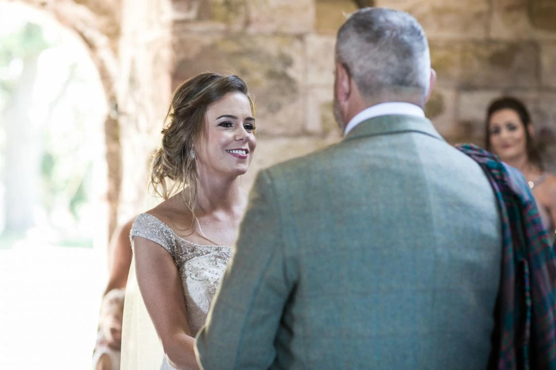 bride smiling at groom during ceremony in church