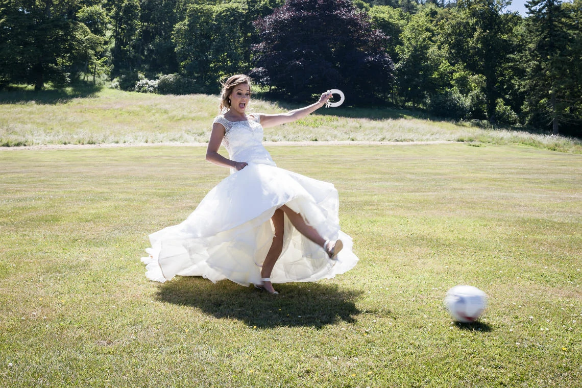 bride Emma kicking a football in the grounds of the venue