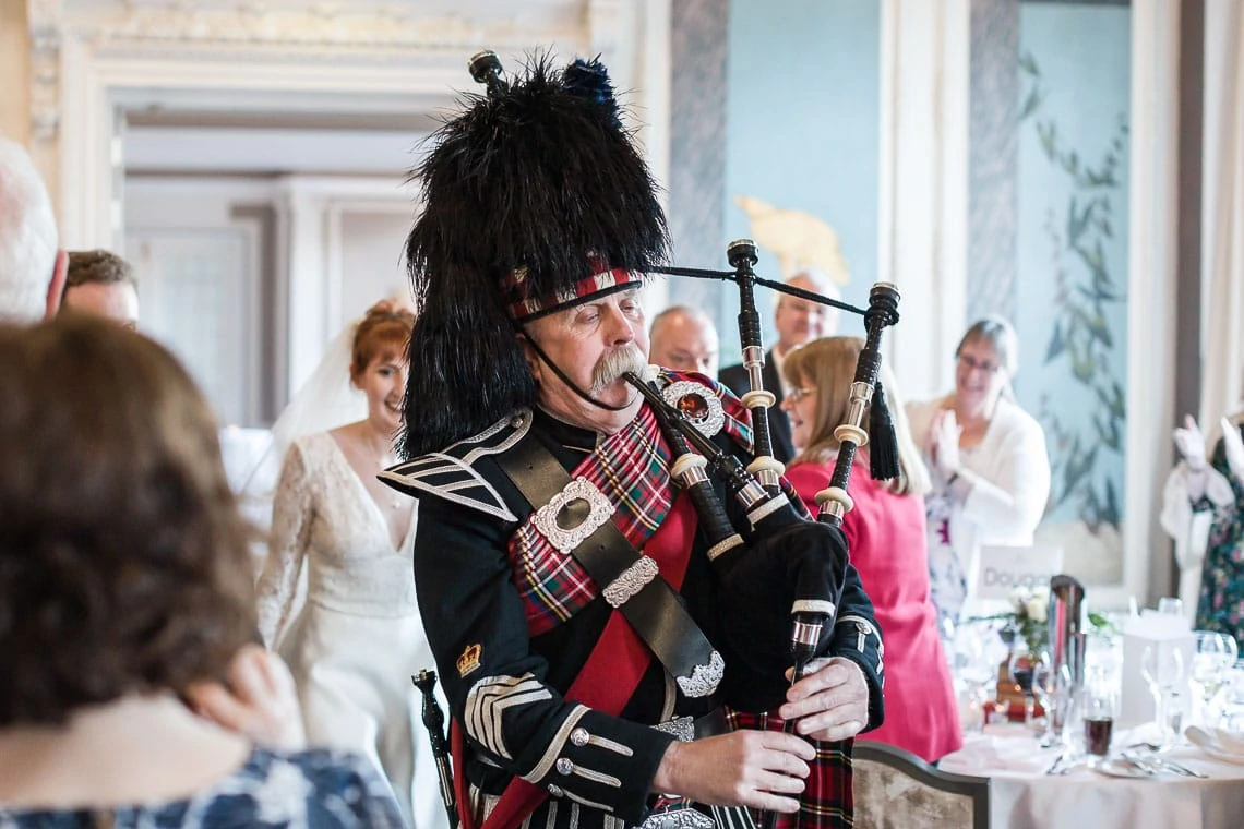 Pipe Major Iain Grant leads the newlyweds into The Castle Suite