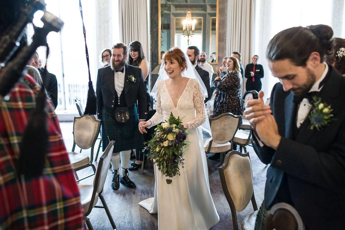 Pipe Major Iain Grant leads the newlyweds into The Castle Suite