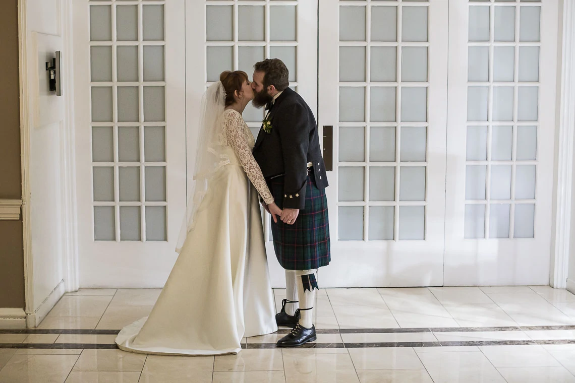 Newlyweds kiss outside The Castle Suite at Waldorf Astoria Edinburgh