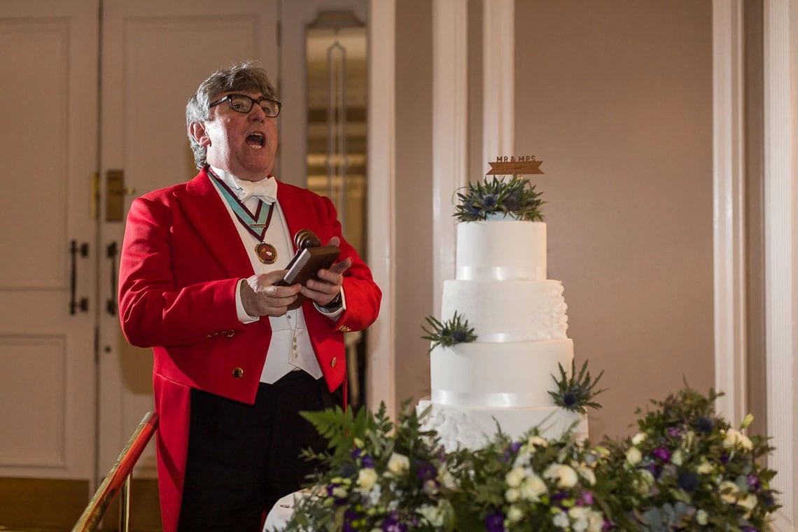 Toastmaster Patrick J. Hayes of The National Association of Toastmasters announces newlyweds cutting the cake