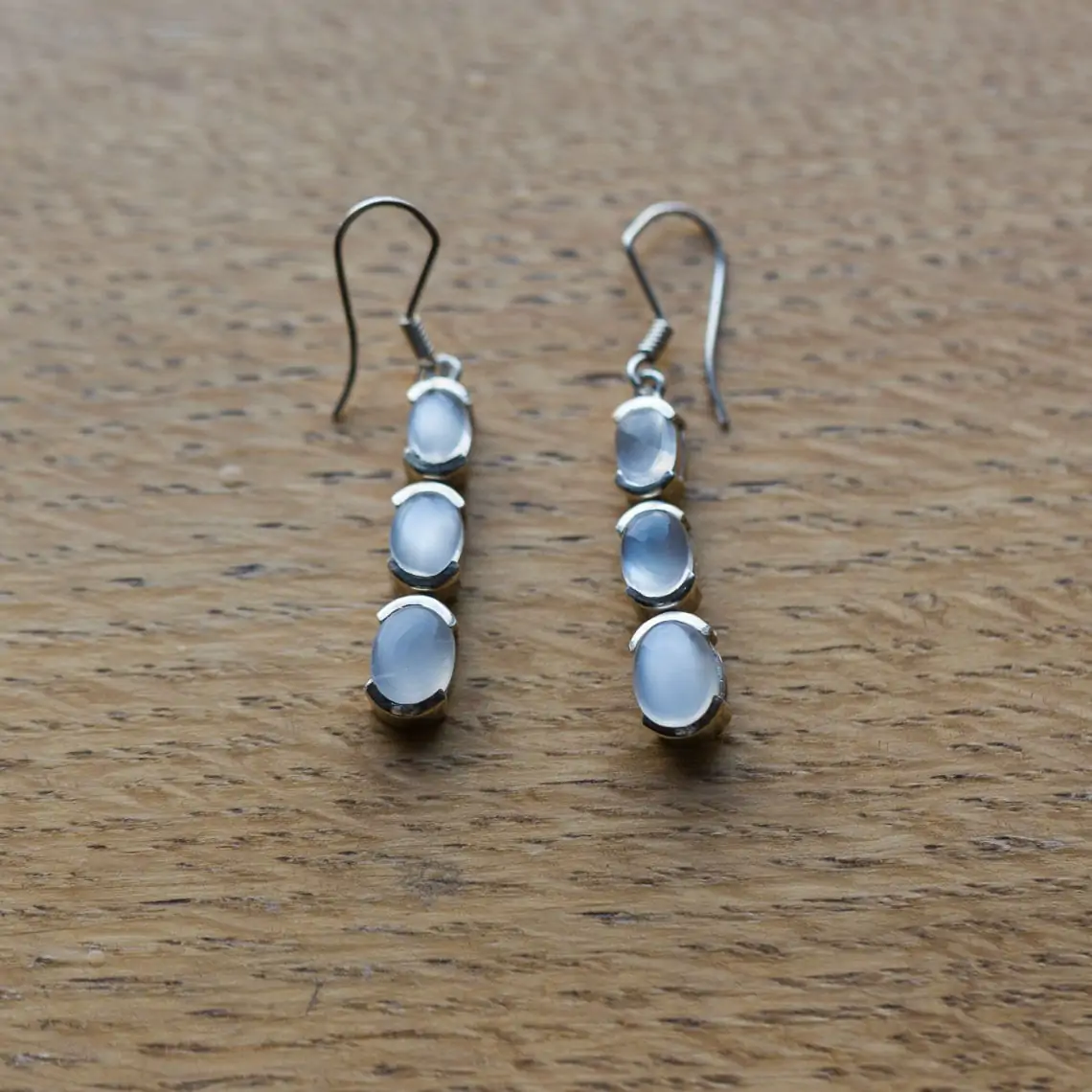 Long three stone silver earrings on wooden background